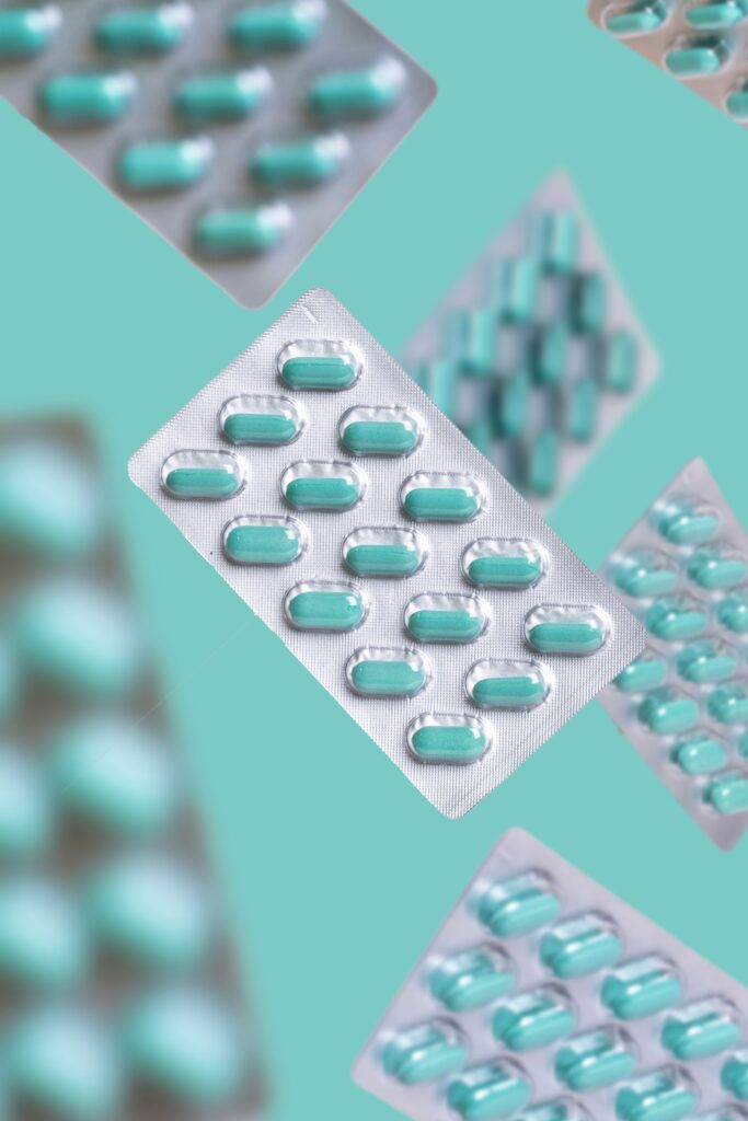 A whimsical arrangement of floating pill blister packs against a teal backdrop, highlighting healthcare themes.